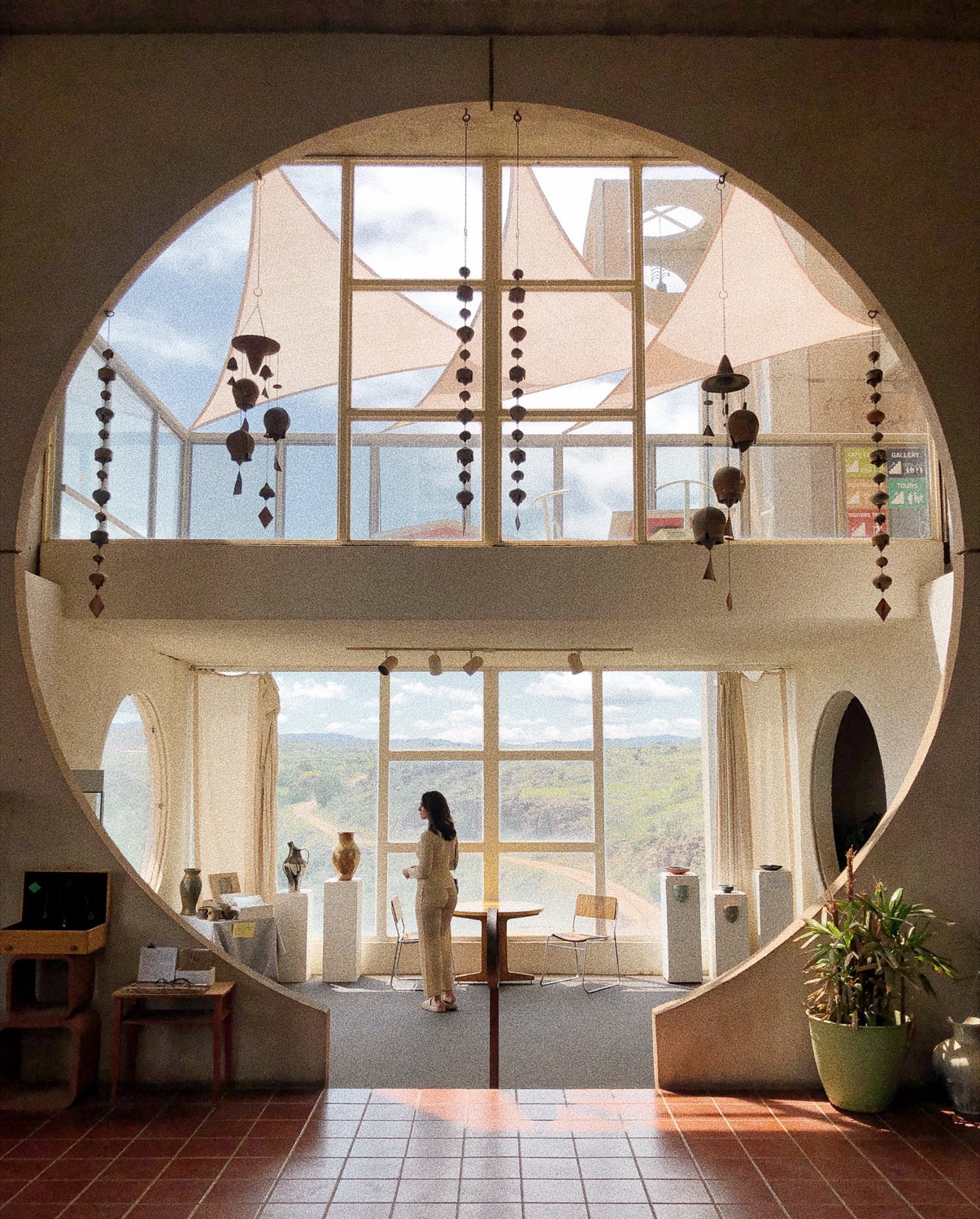 Inside Arcosanti: the vaulted gallery, with Soleri windbells and the high-desert view. The place itself, the hosting that earns about 38% of revenue.