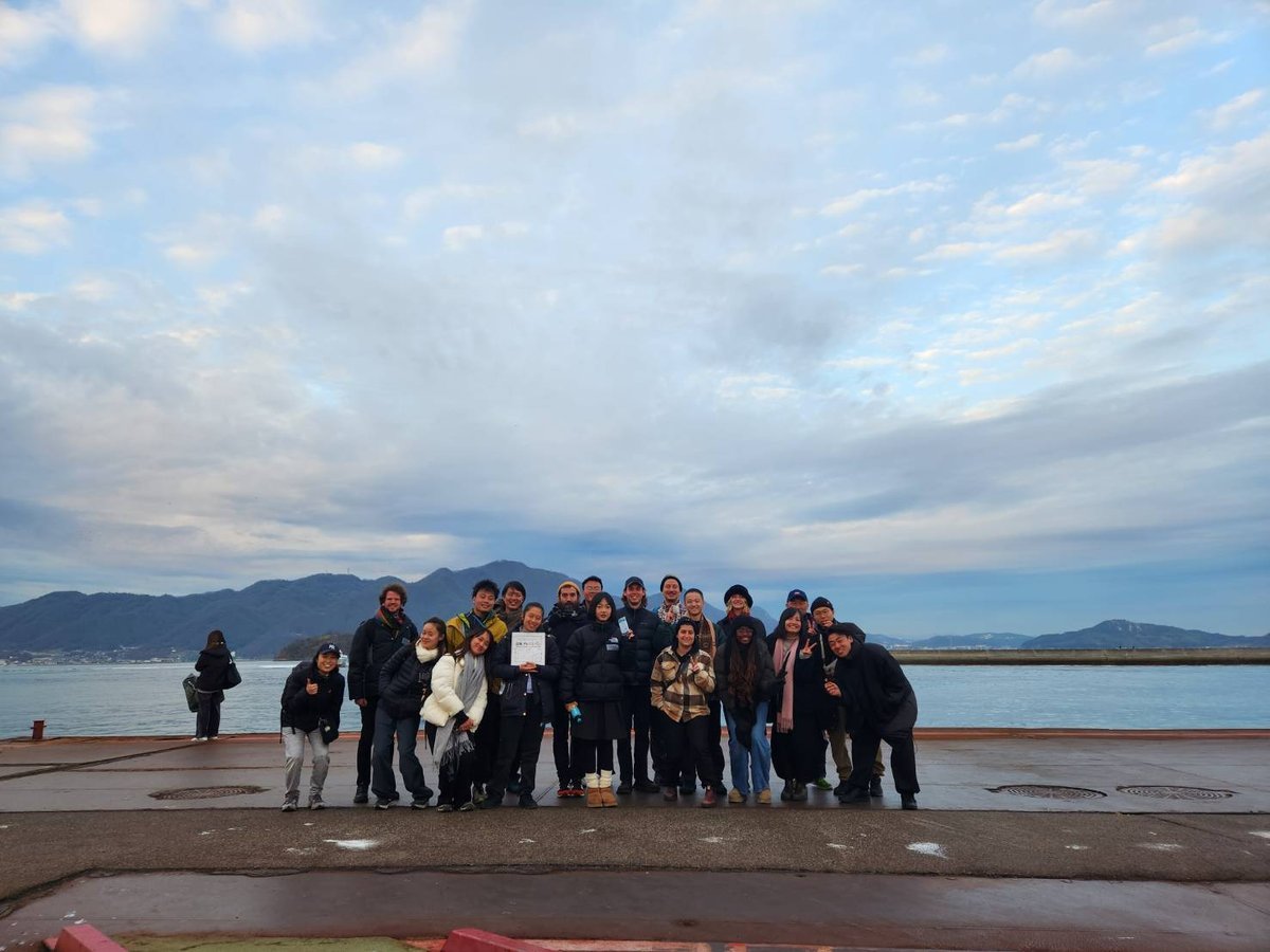 A studio cohort gathered on the Sunoue pier with the sea behind.